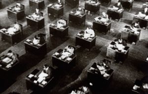 People sitting at rows of desks, black and white